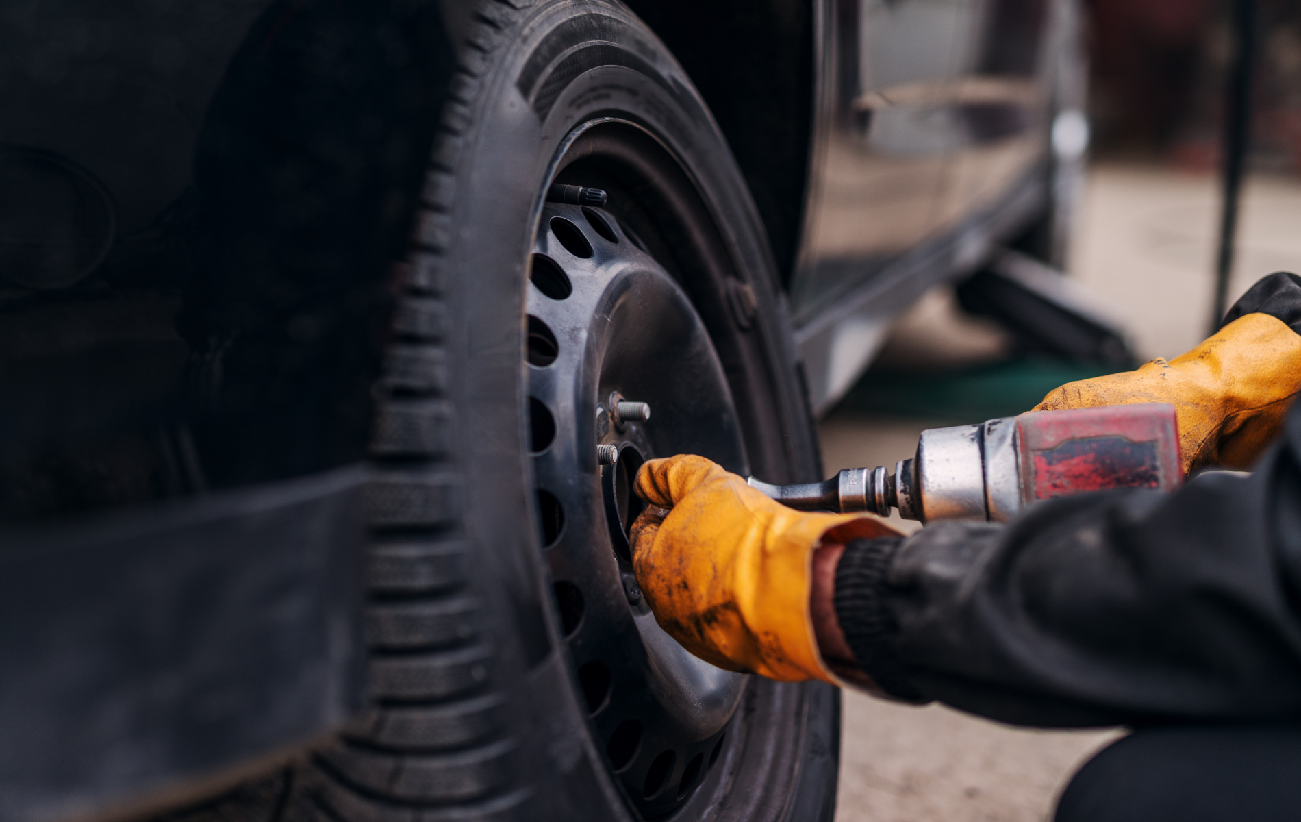 A man is changing a tire on a car with a wrench.