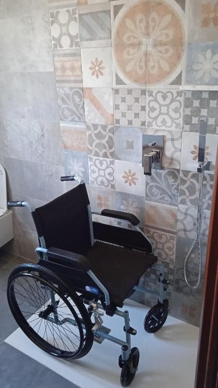 Una sedia a rotelle è posizionata in un bagno accanto a un water.