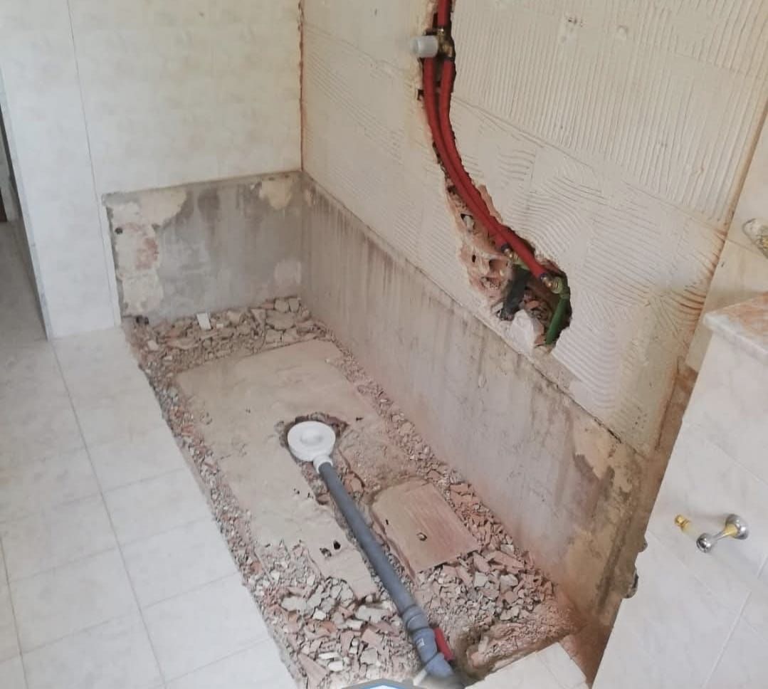 Un bagno con un buco nel muro e un tubo che esce da lì.