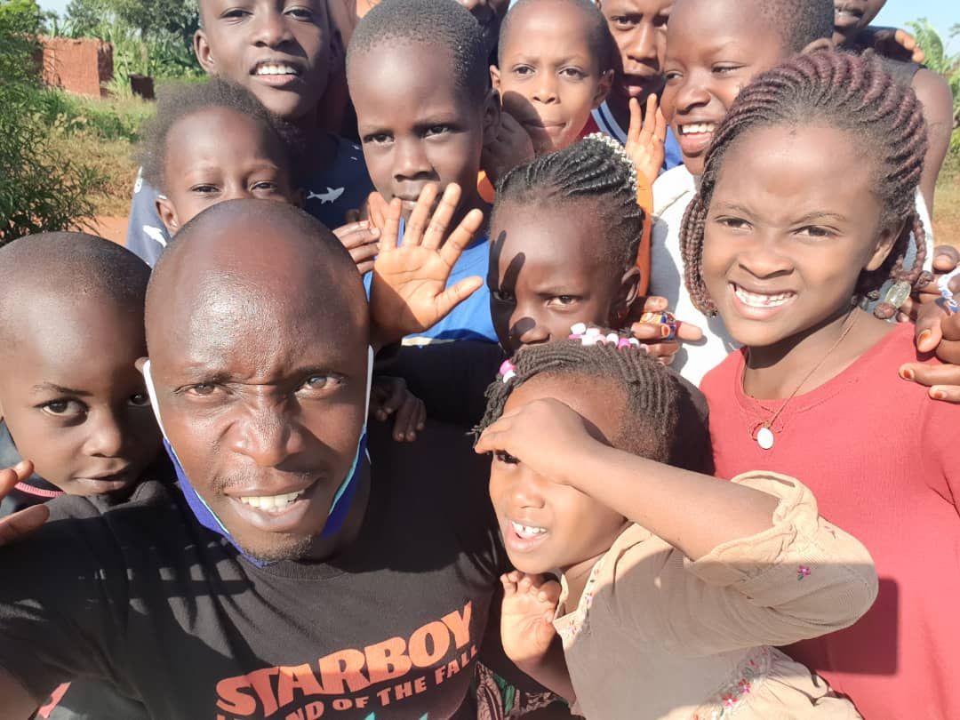 A man wearing a starboy shirt is surrounded by children
