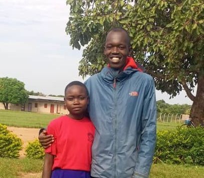 A man in a blue jacket is standing next to a boy in a red shirt.