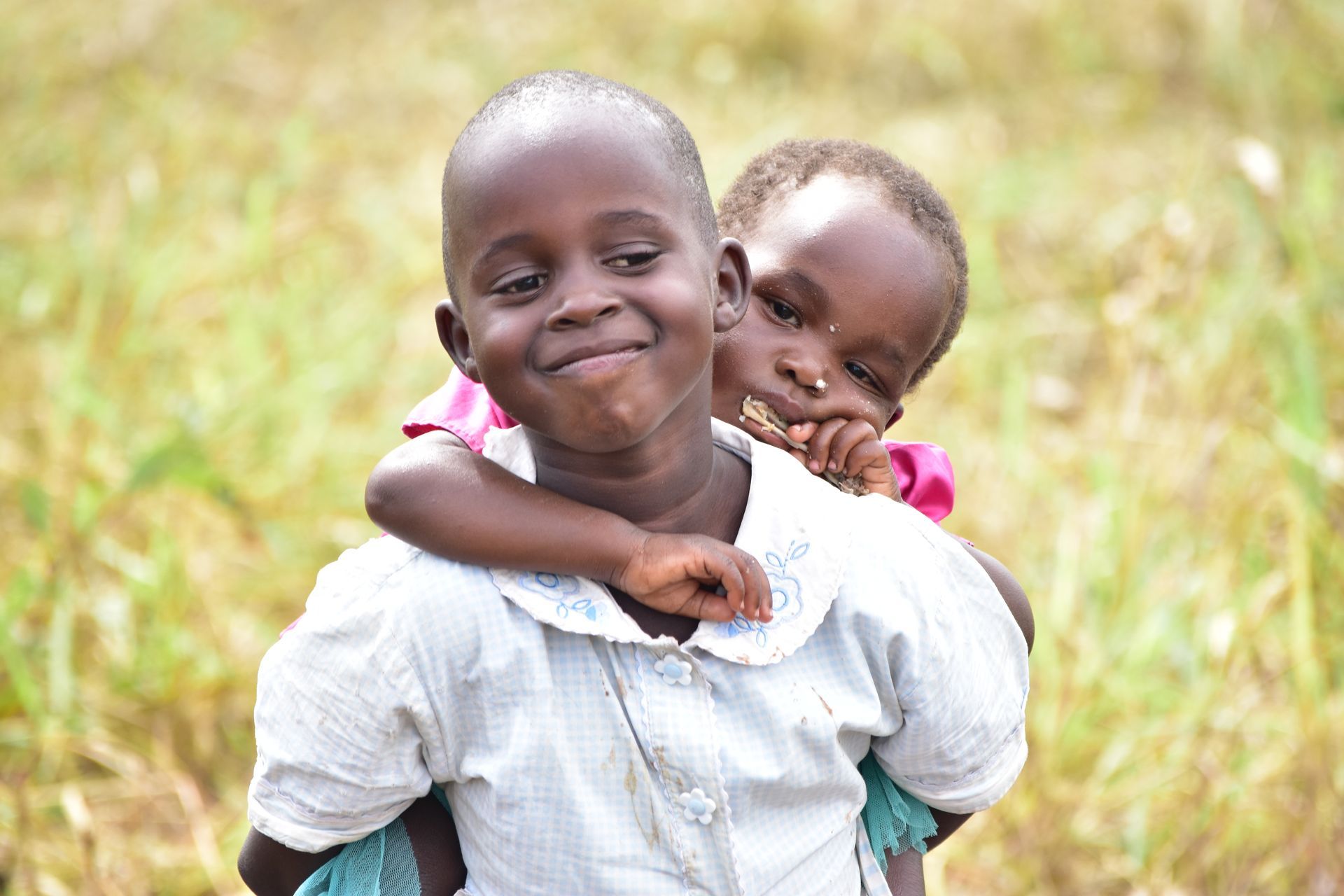 A boy is carrying a little girl on his shoulders.