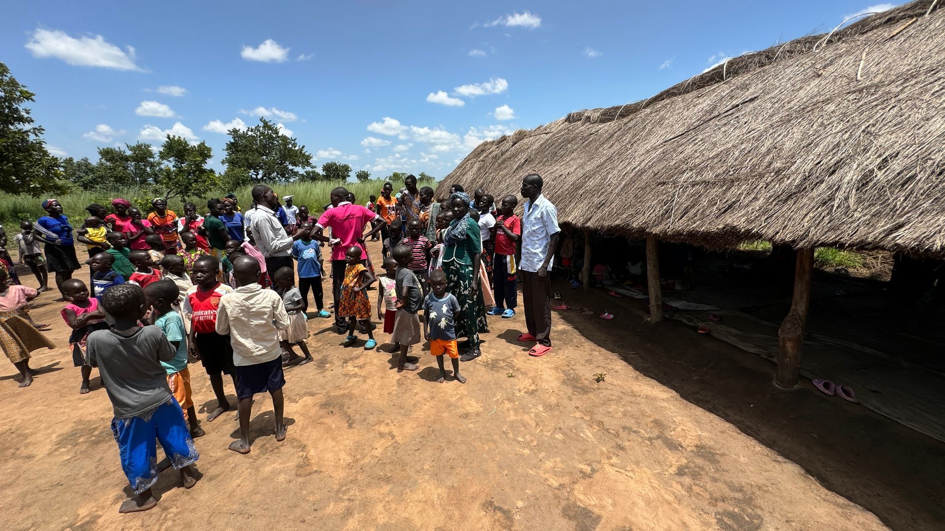 A group of people standing in front of a thatched building
