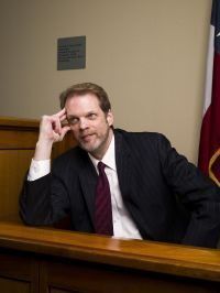 A man in a suit and tie is sitting in a courtroom.