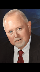 A man in a suit and tie is looking at the camera.