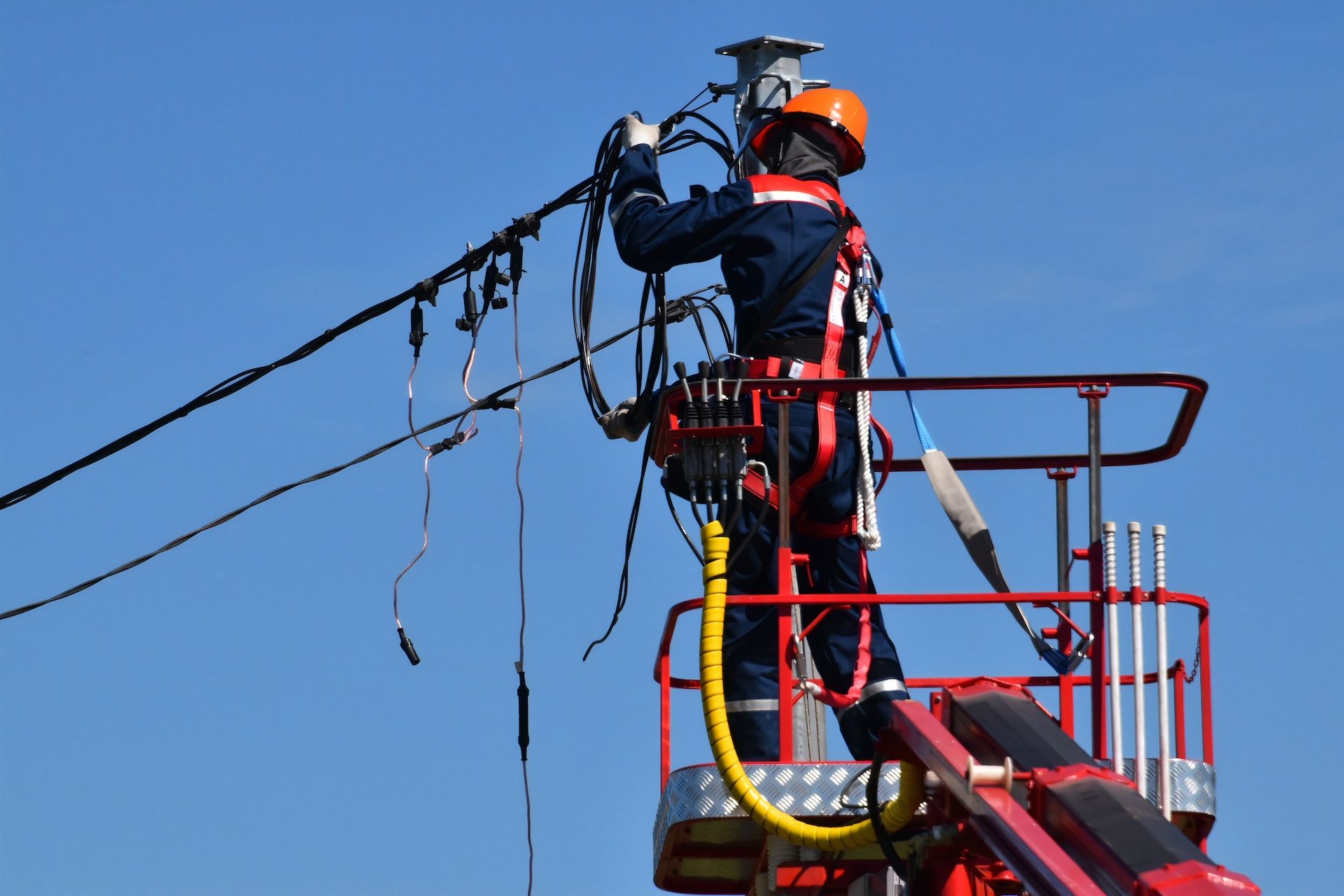 A man is working on a power line on a crane.