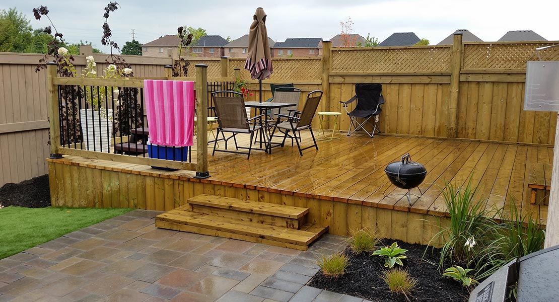 A wooden post is sitting in the dirt next to a fence.