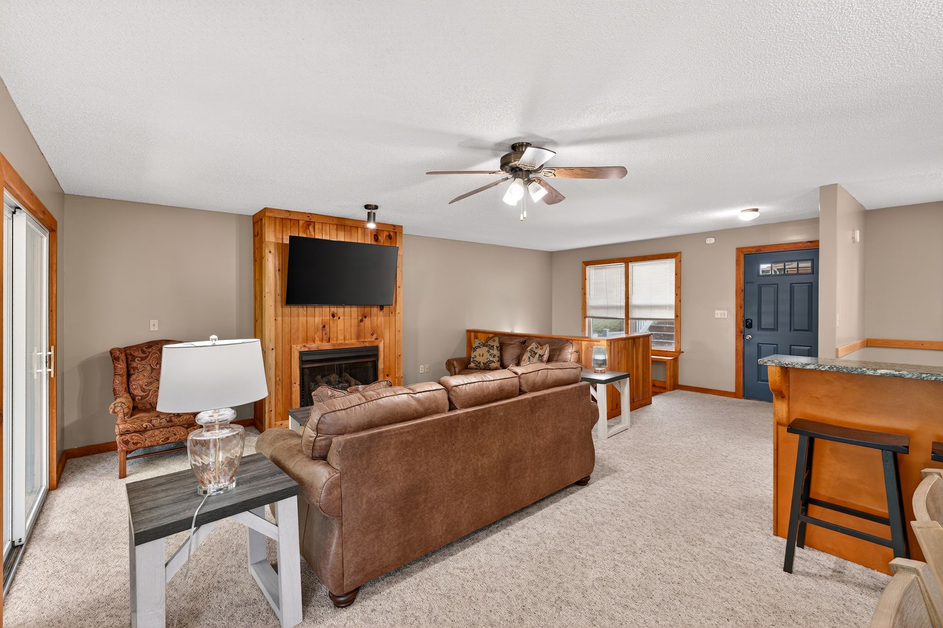 Cozy living room with fireplace, brown sofa, beige walls, and wood accents.