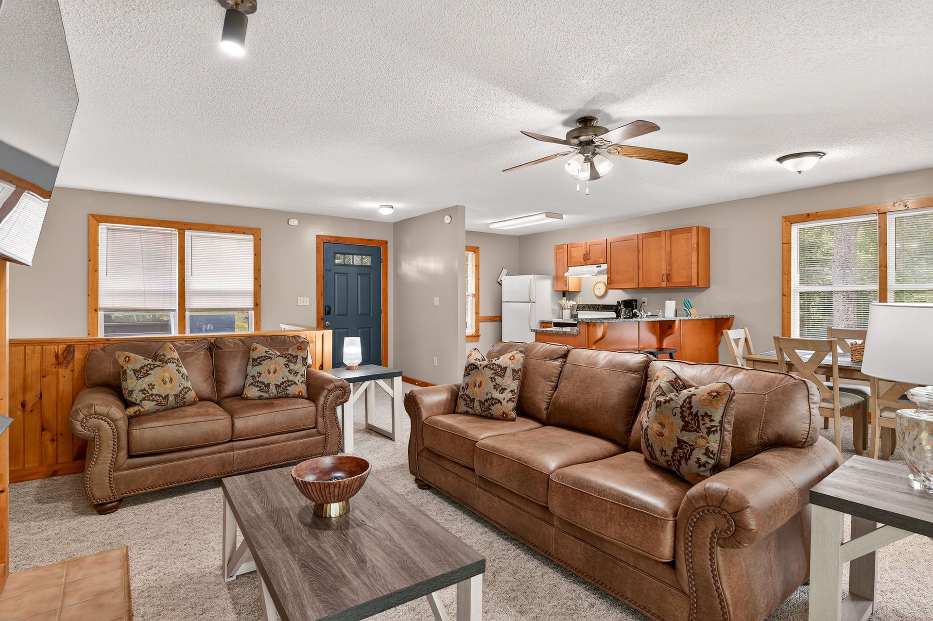 Cozy living room with two brown leather sofas, a coffee table, and a view into the kitchen.