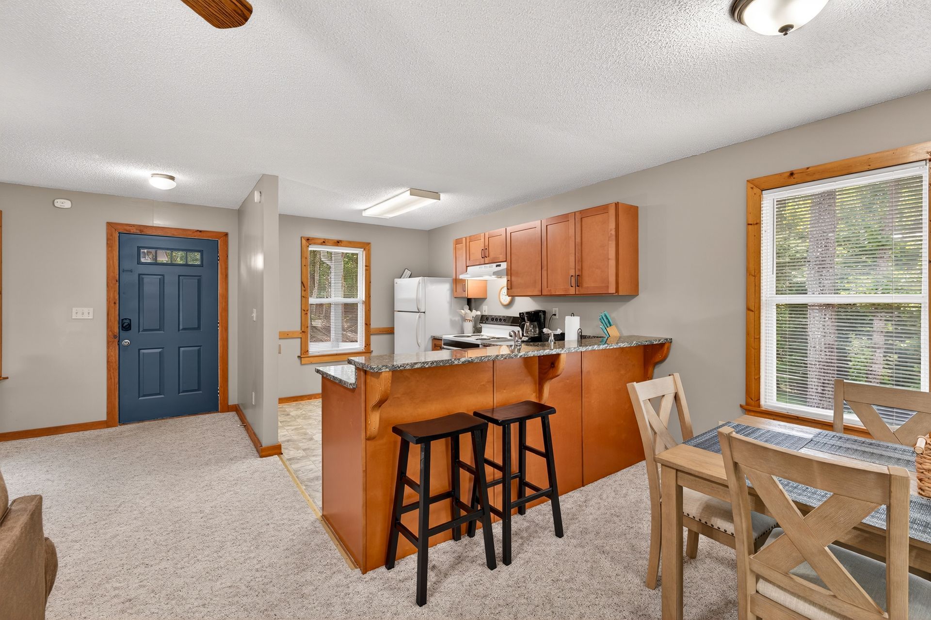Kitchen and dining area with blue door and wood accents. Features a breakfast bar and table.