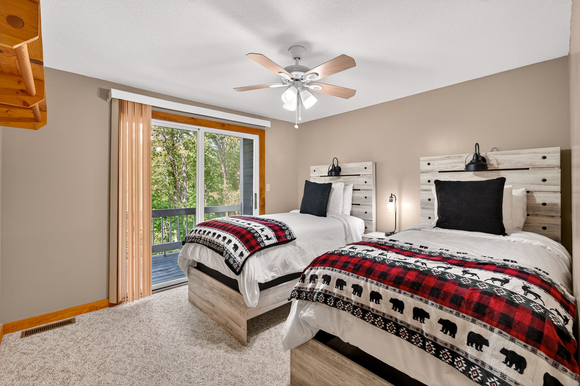 Bedroom with two twin beds, red plaid blankets, sliding glass door to a deck.