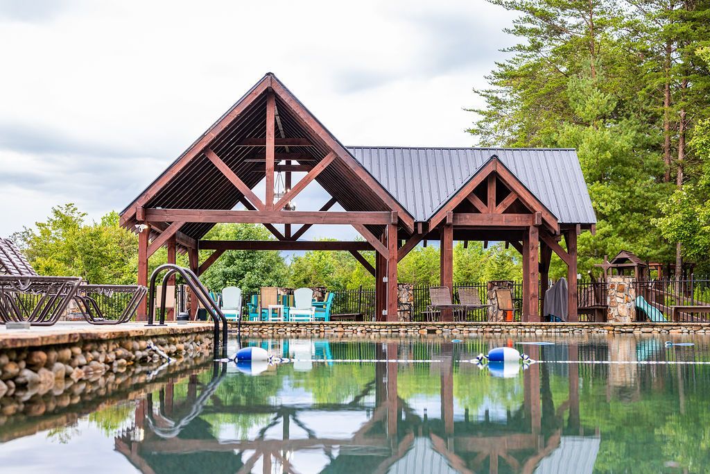 Swimming pool with wooden gazebo; mountain view in background.