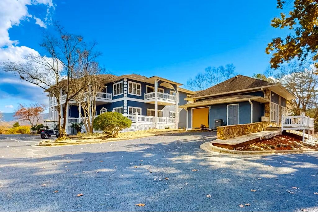 Two-story blue house with white railings and a yellow garage on a blue sky day.