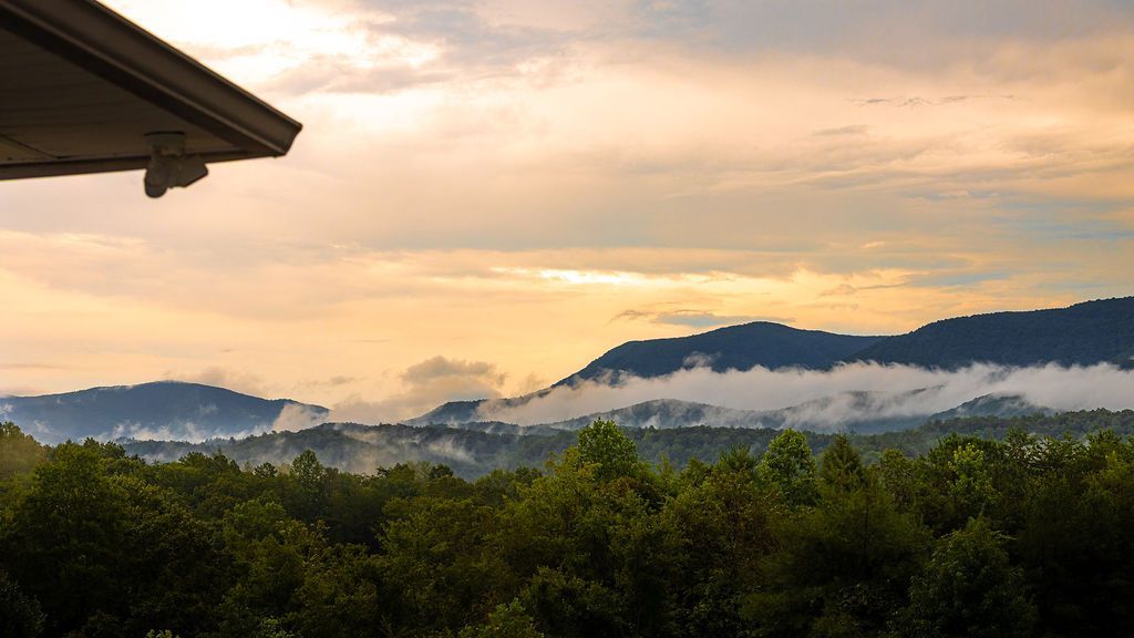 Sunrise over misty mountains and a lush forest.