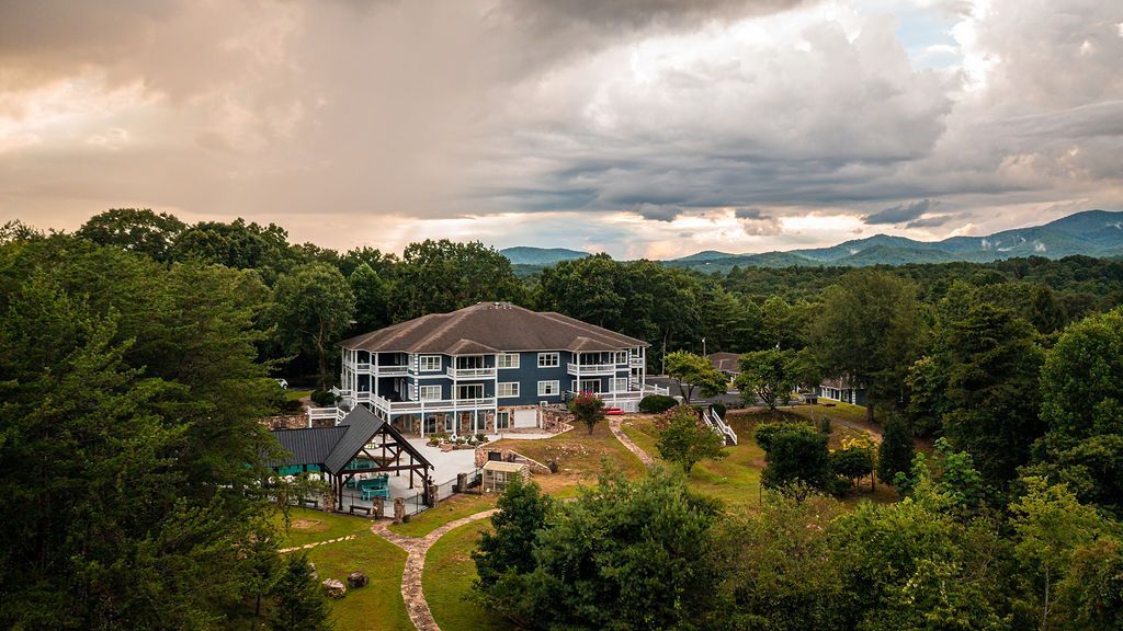 Large blue-gray building amidst green trees under cloudy skies; outdoor setting with a path.
