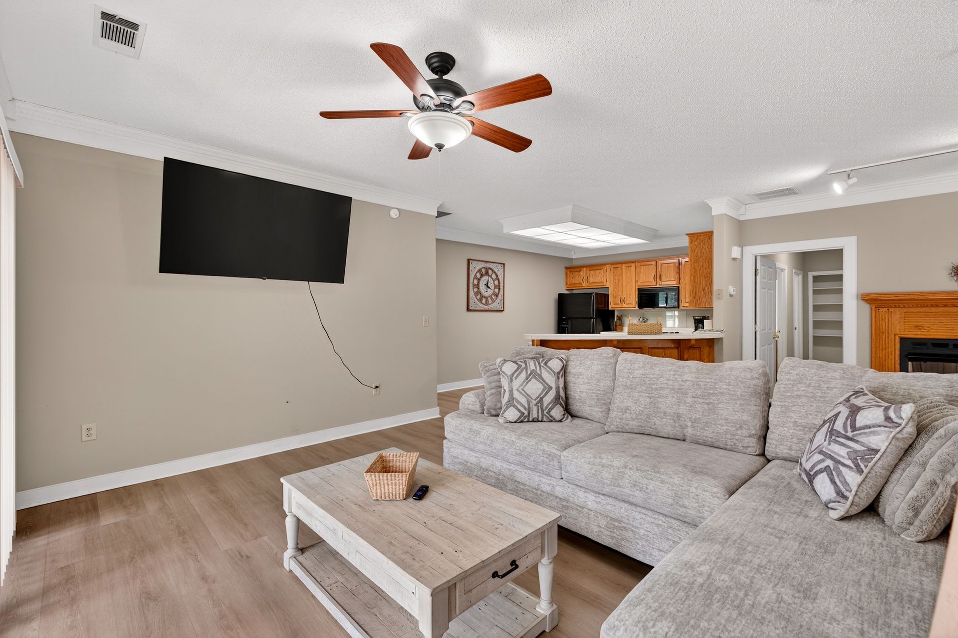 Living room with gray sectional, TV, coffee table, and a view into the kitchen.