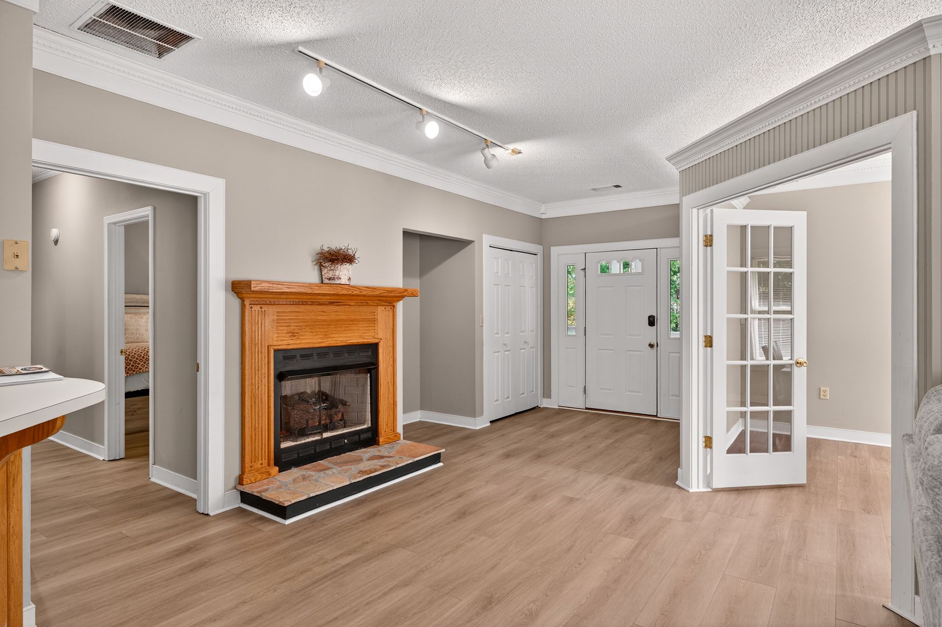 Living room with fireplace, light wood floors, and white trim. Doorway leads to the outdoors.