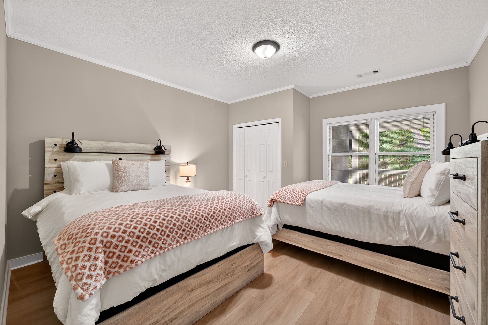 Bedroom with two beds, light wood furniture, beige walls, and a white ceiling.