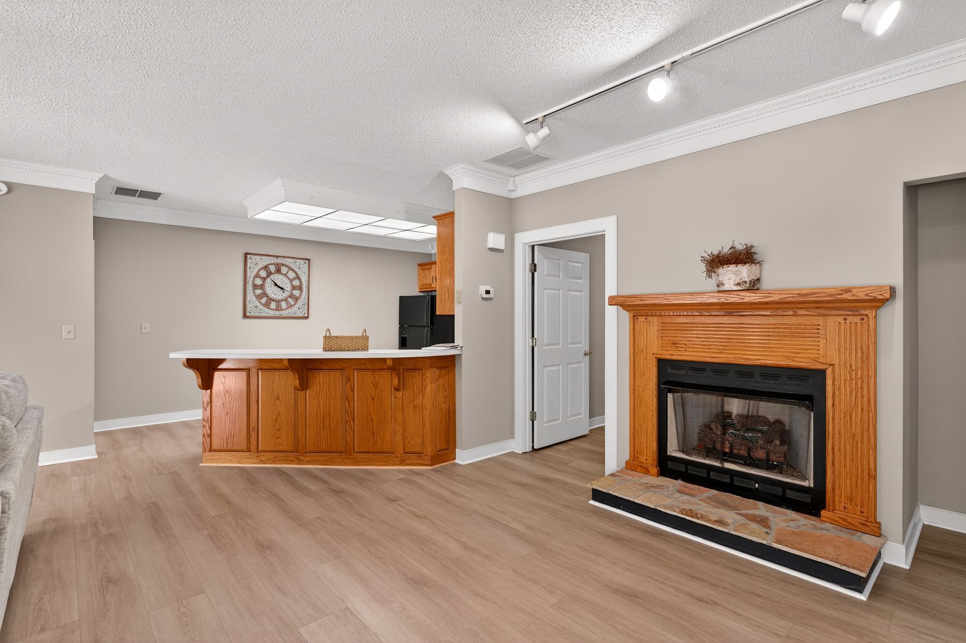 Living room with wooden fireplace, bar, and light-colored walls.