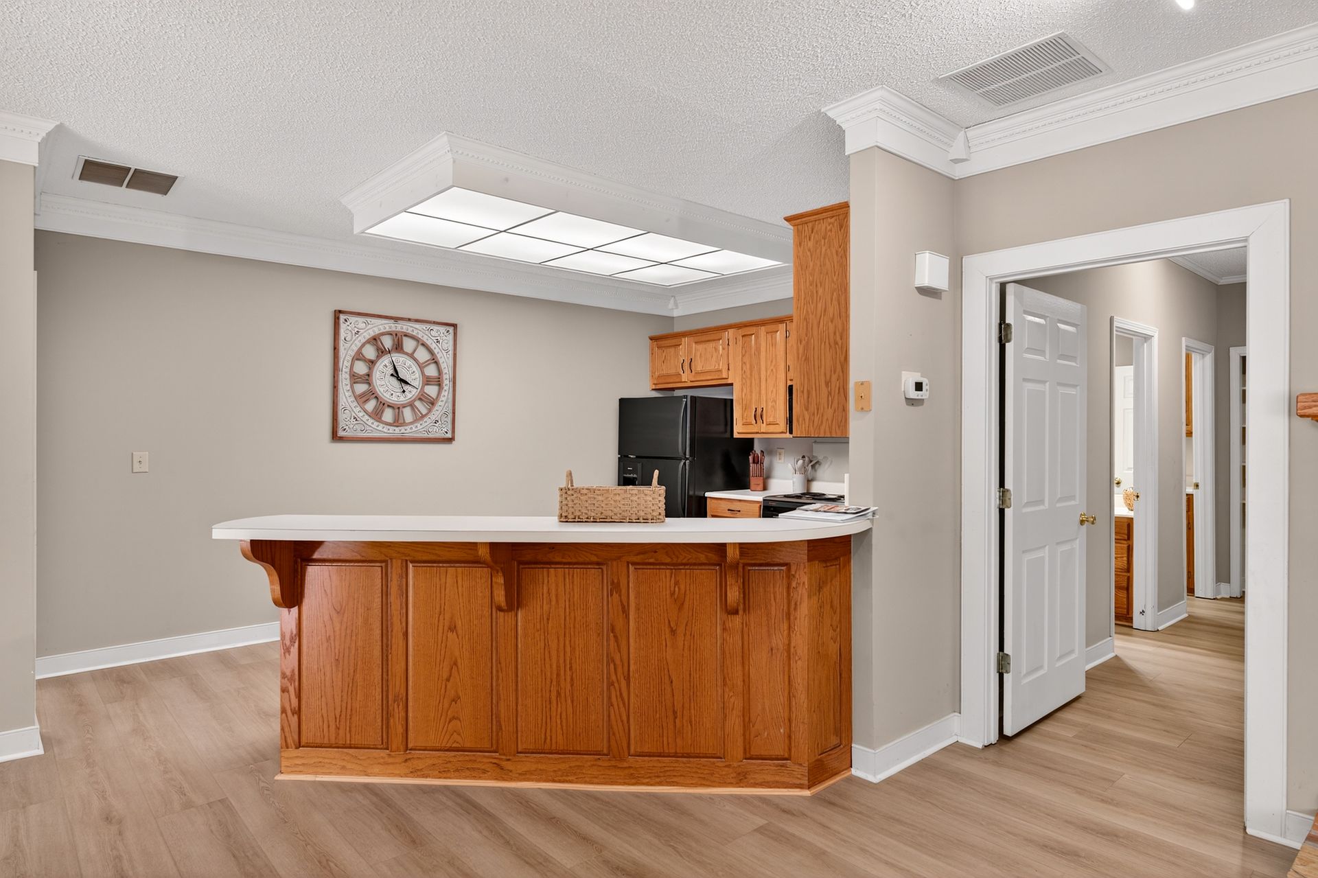 Kitchen with wooden cabinets and a breakfast bar. Doorway leads to a hallway.