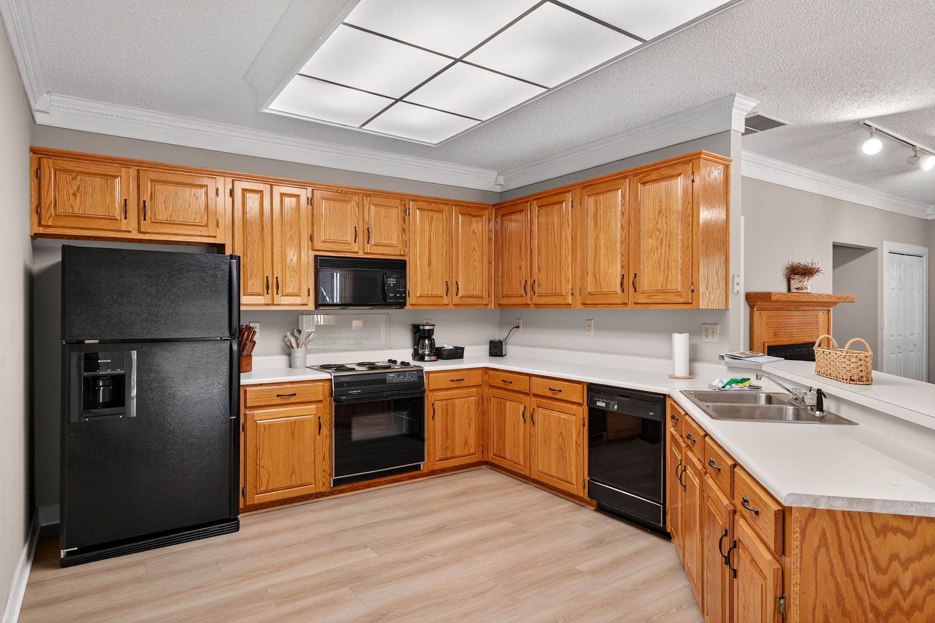Kitchen with wood cabinets, black appliances, and white countertops.