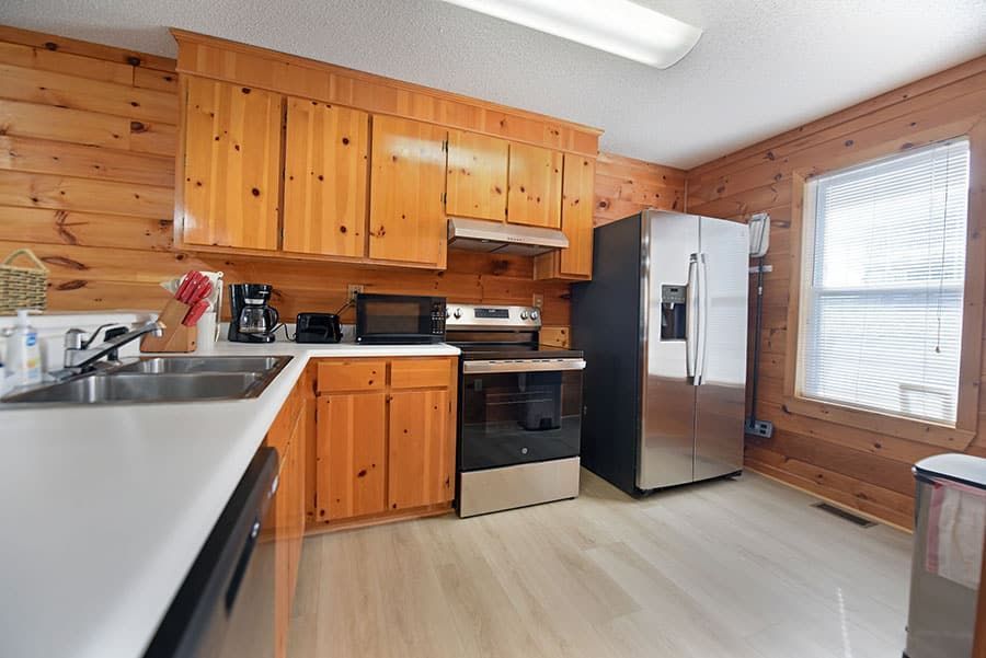 Kitchen with wood paneling, stainless steel appliances, and a window.