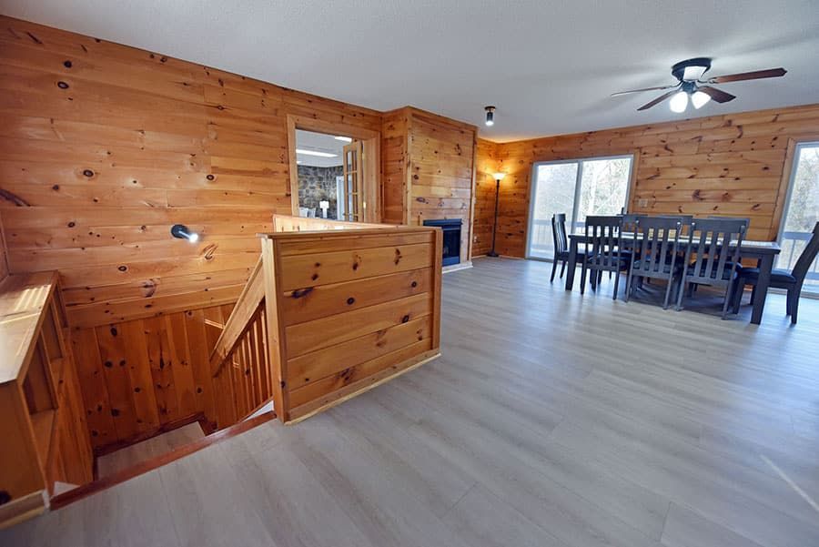 Wooden-paneled interior with staircase, dining table, and sliding glass doors leading outside.