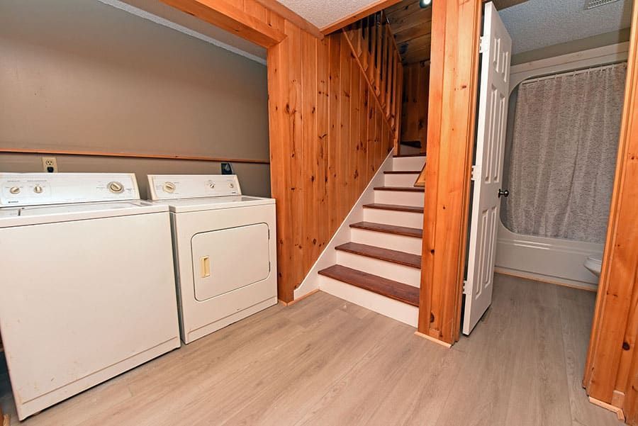 Laundry area with washer, dryer, wooden stairs, and door to a bathroom.