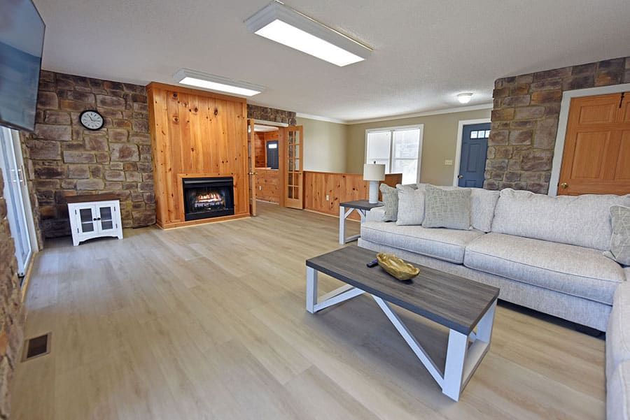 Living room with fireplace, stone walls, light wood flooring, and a white couch.