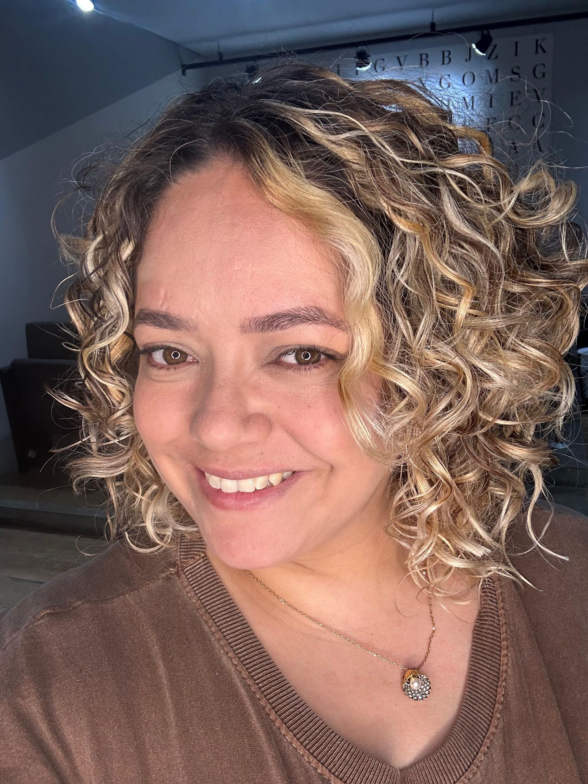 Uma mulher vestindo uma camiseta branca e brincos de argola está sorrindo.