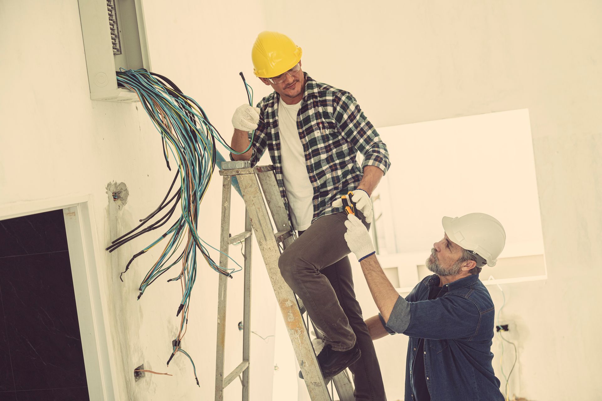 Local electrical contractors preparing the wires in a house to connect to the breaker. Local electrical contractors preparing the wires in a house to connect to the breaker.