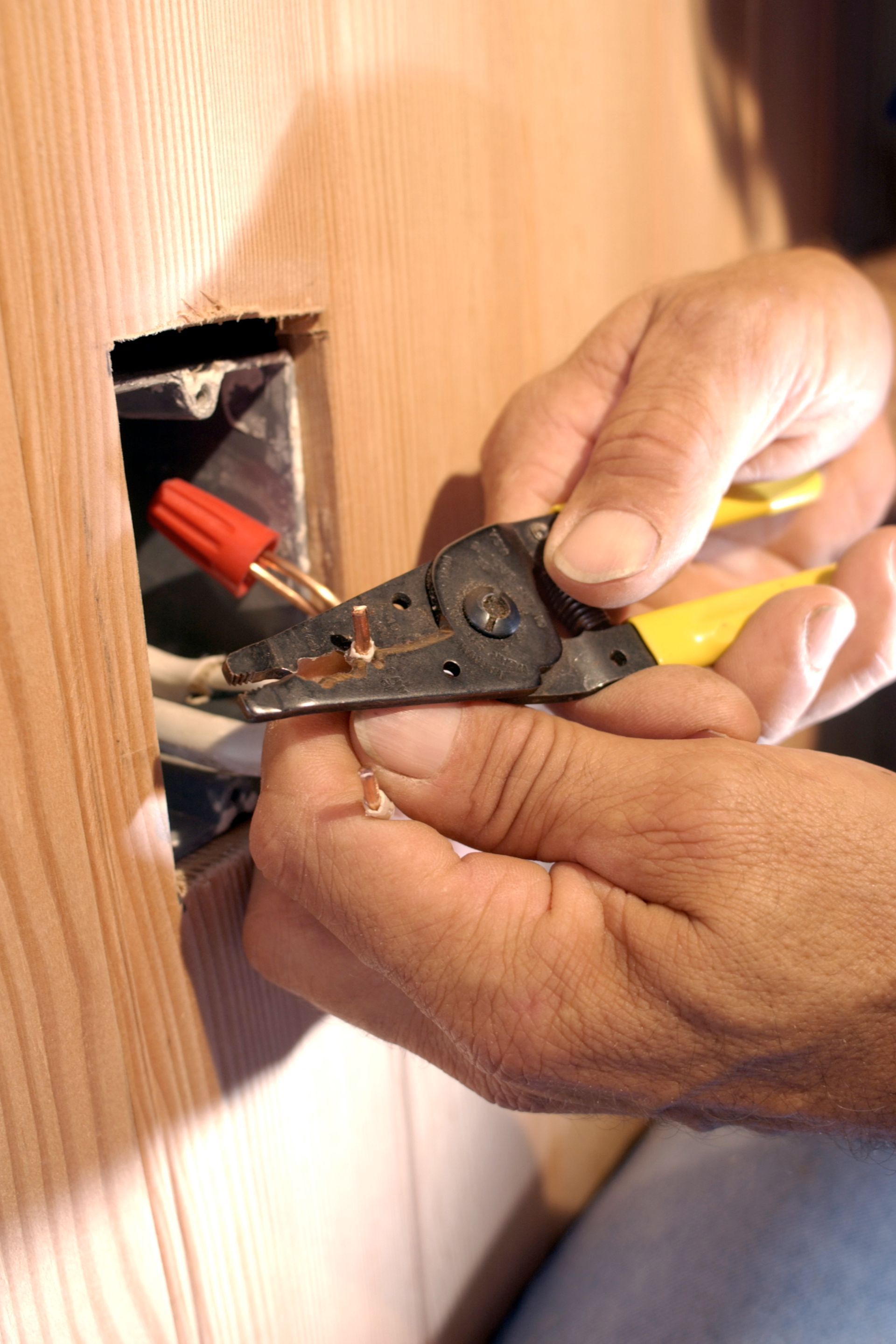 Close-up of a commercial electrical contractor as he works on an electric plug with a pair of pliers.