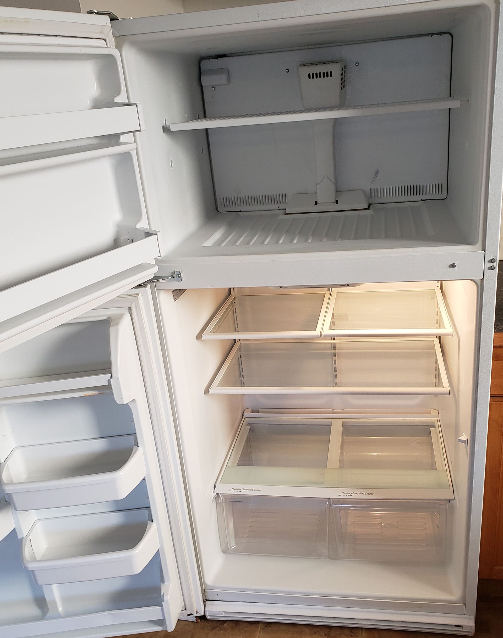 Man cleaning glass window with a squeegee, outdoor setting with plants and seating.