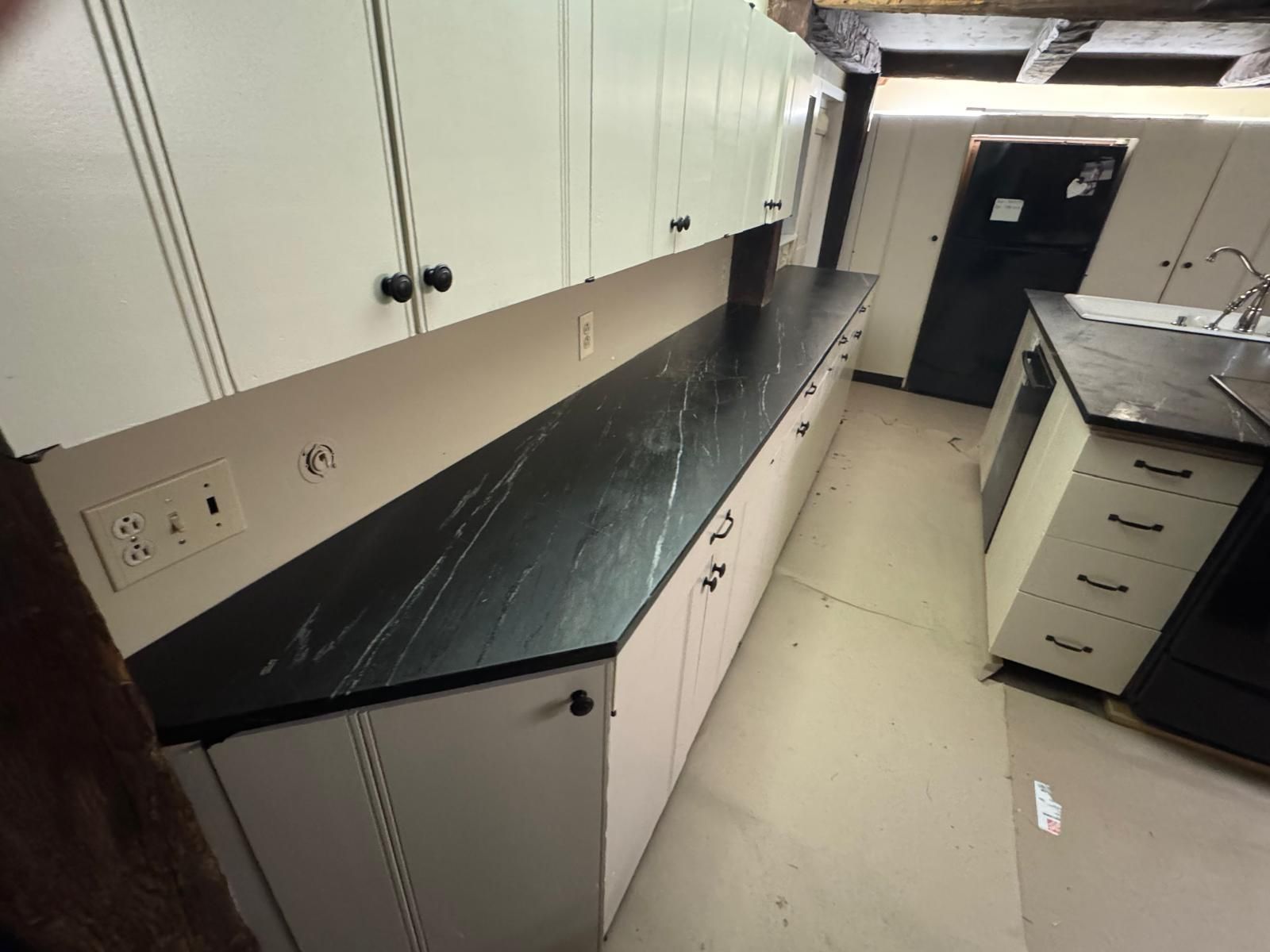 Kitchen with white cabinets, dark countertop, and appliances.