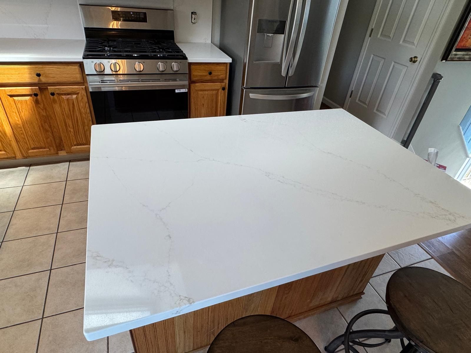 Kitchen with a white countertop island and stainless steel appliances.