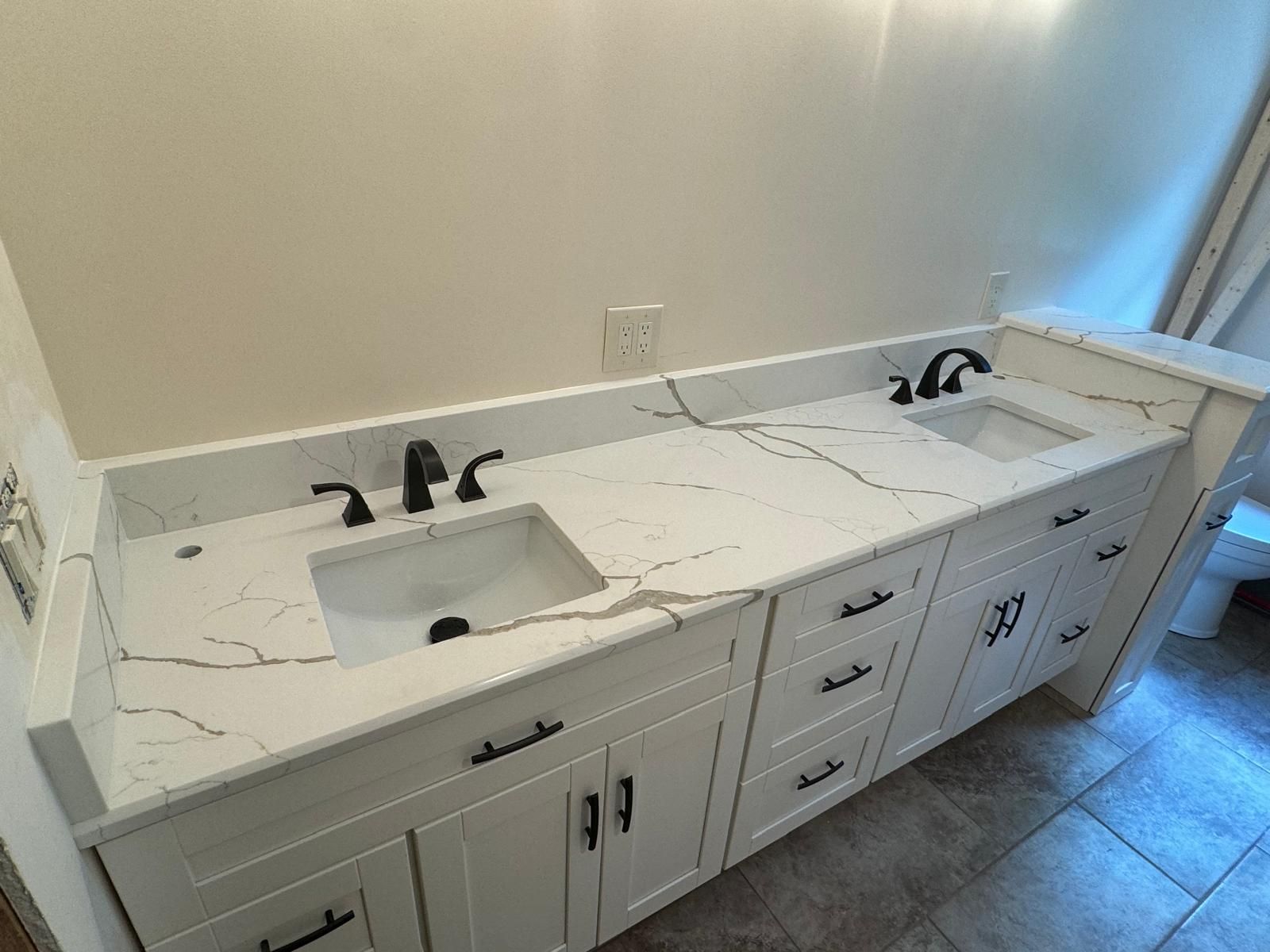 White double vanity with black fixtures and marble-look countertop.