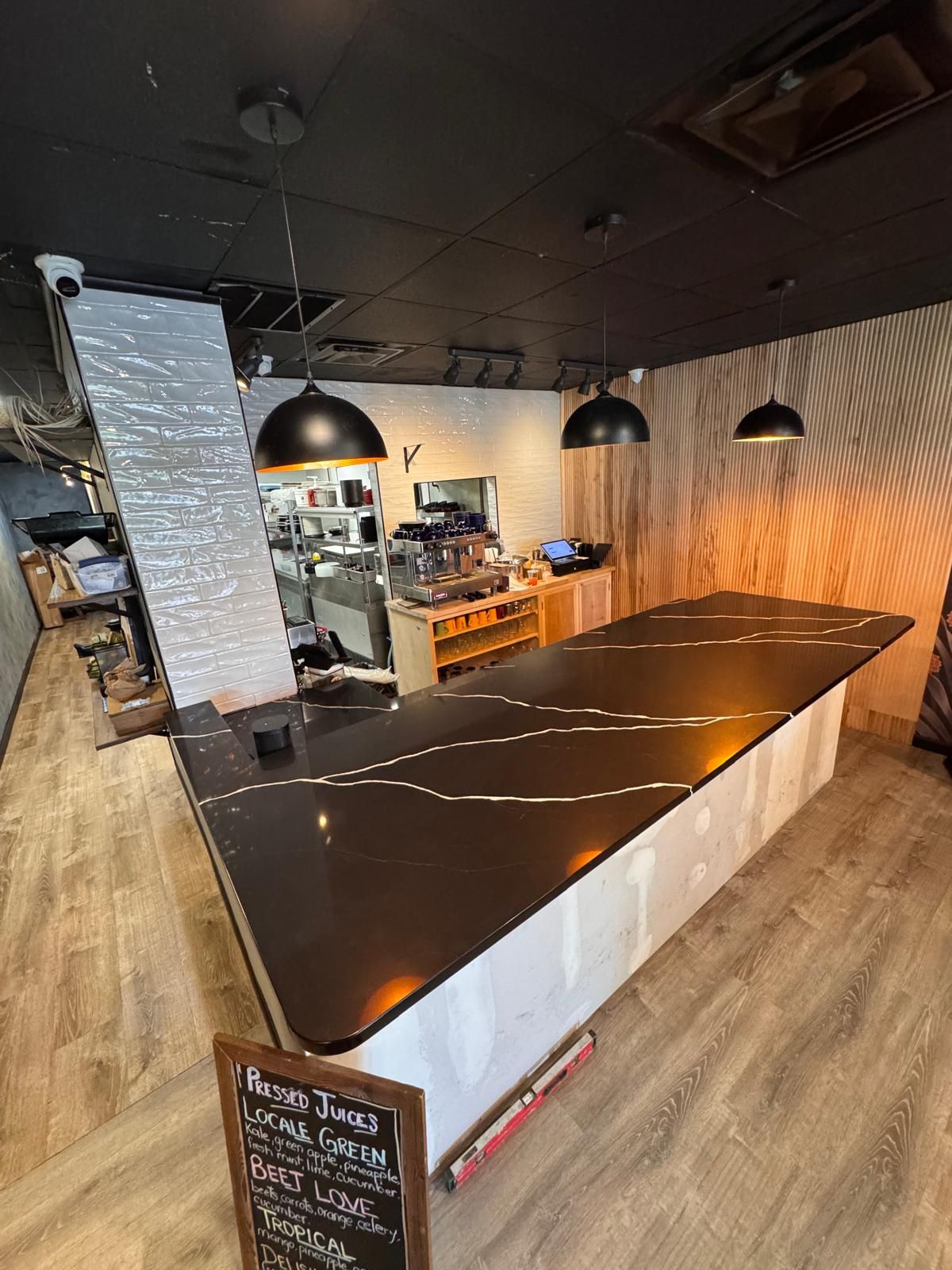 A coffee shop with a dark countertop and three pendant lights.