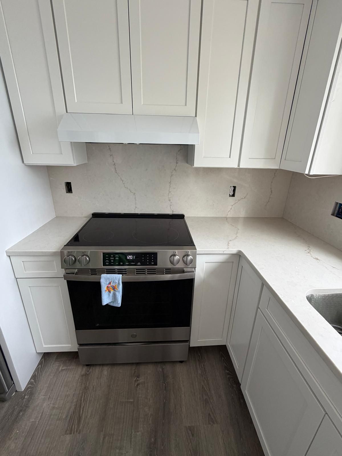 Kitchen with white cabinets, stainless steel oven, and light-colored countertop and backsplash.