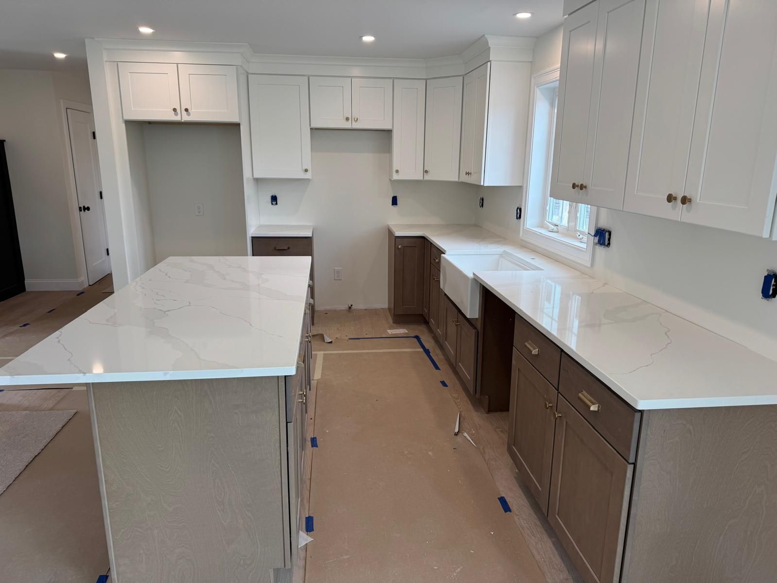Kitchen with white countertops and cabinets, brown lower cabinets, and an island.