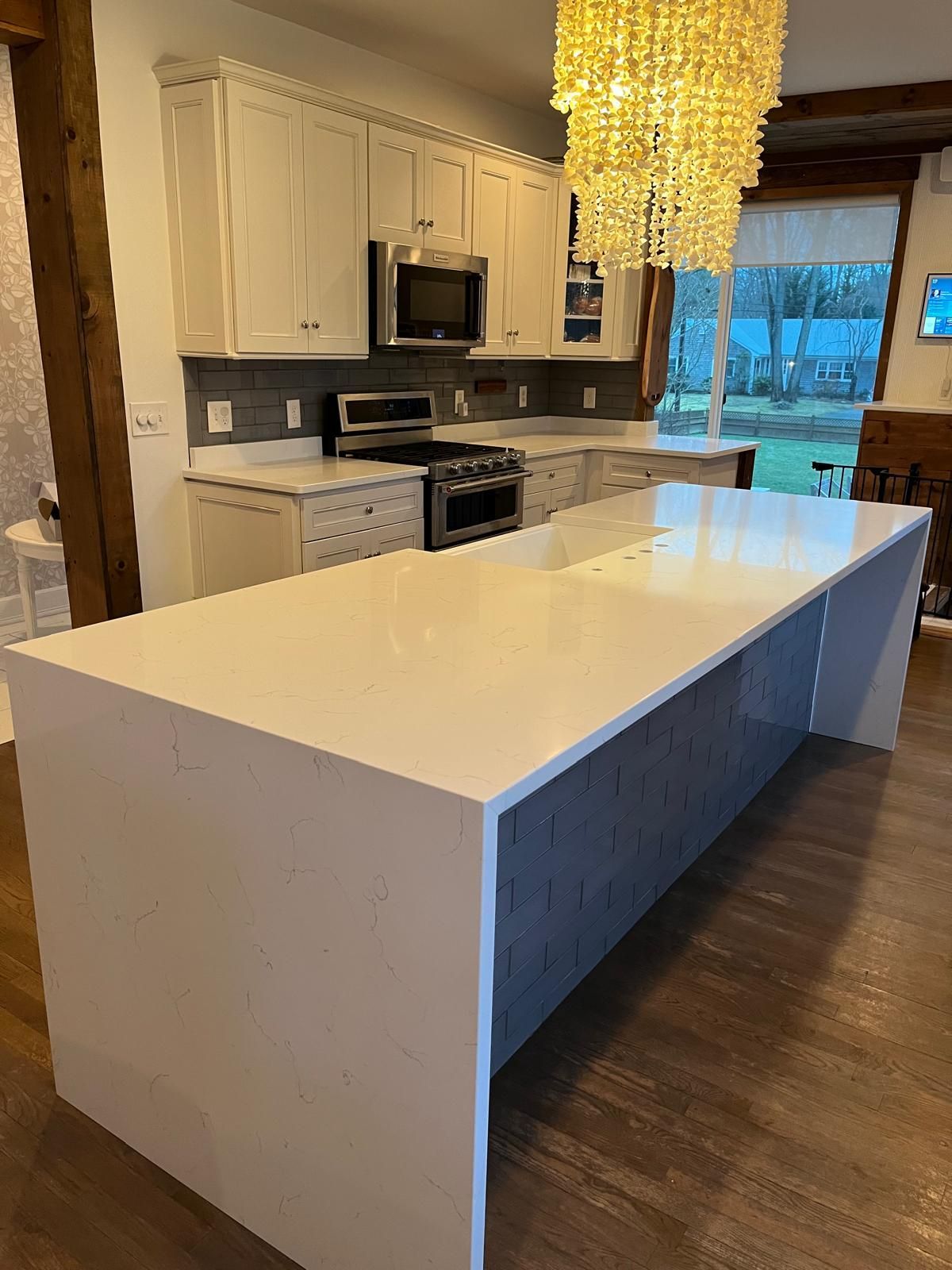 White kitchen with a large island, cabinets, appliances, and a chandelier.