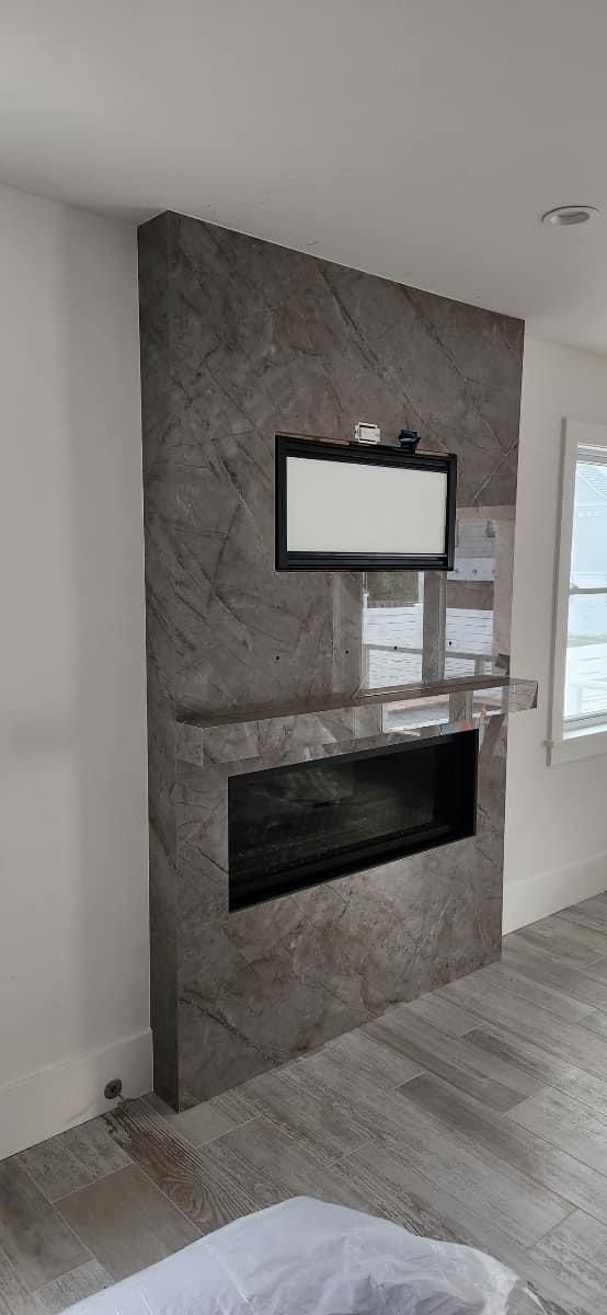 A modern fireplace with a gray stone facade, a black-framed screen, and a long dark hearth.