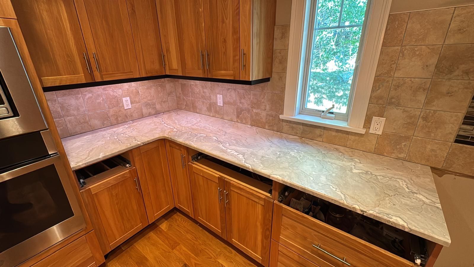 Kitchen with wooden cabinets, light-colored countertops, and a window.