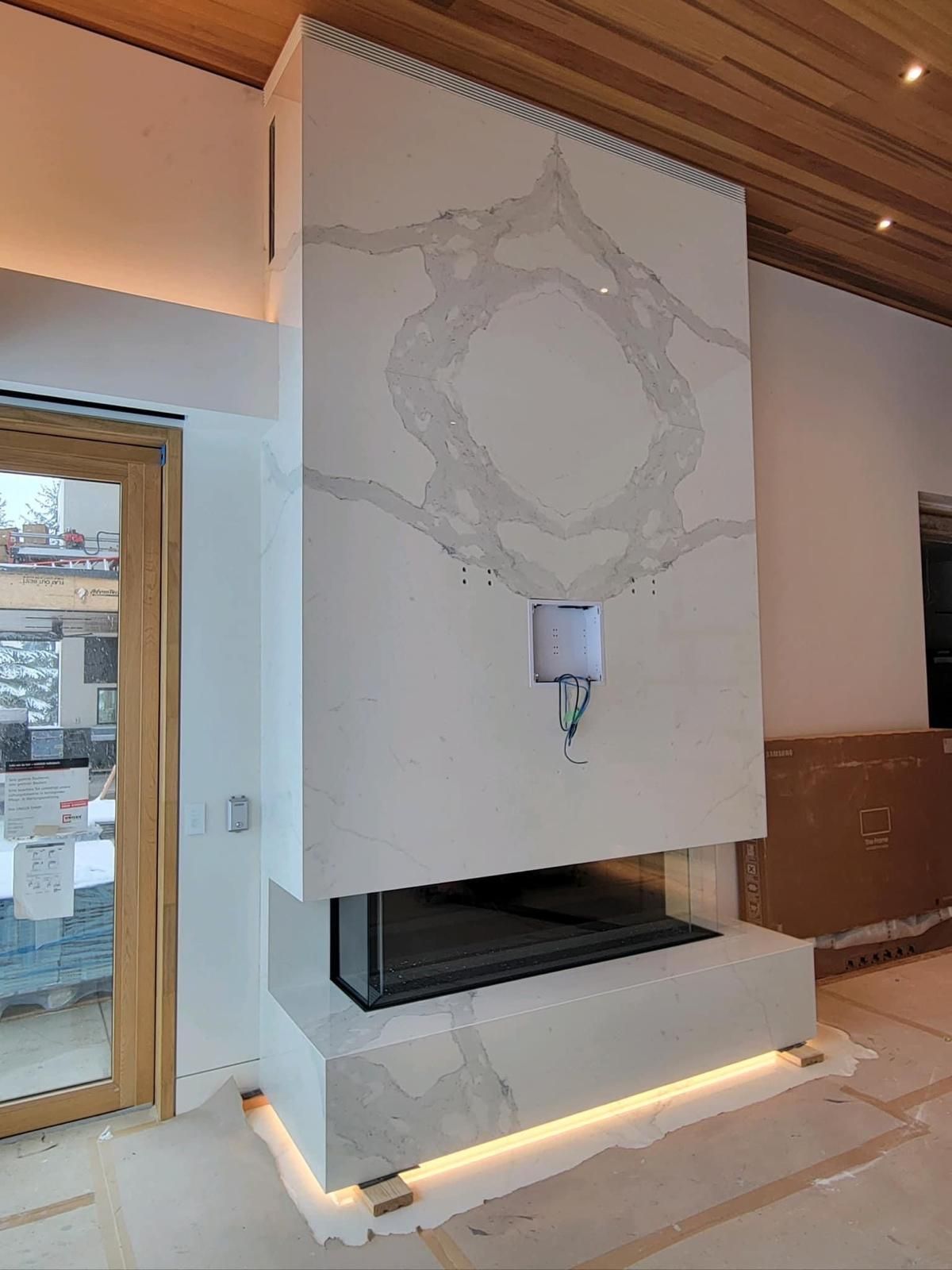 Modern fireplace with white stone facade, built-in black firebox, and decorative gray veining, lit with warm LEDs.