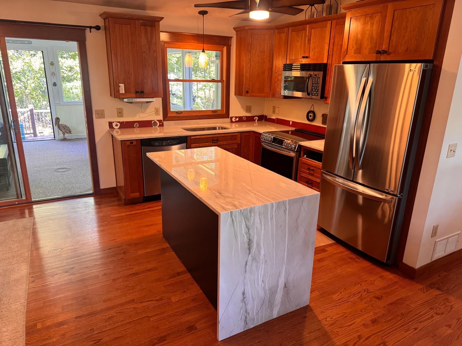 Kitchen with wood cabinets, stainless steel appliances, and a marble island.