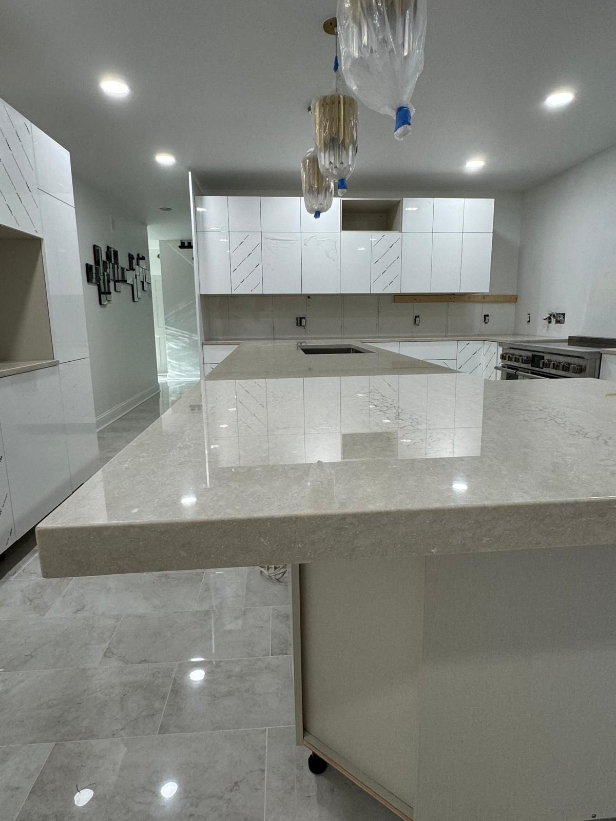 Modern kitchen with a large light-colored island, white cabinets, and pendant lights.
