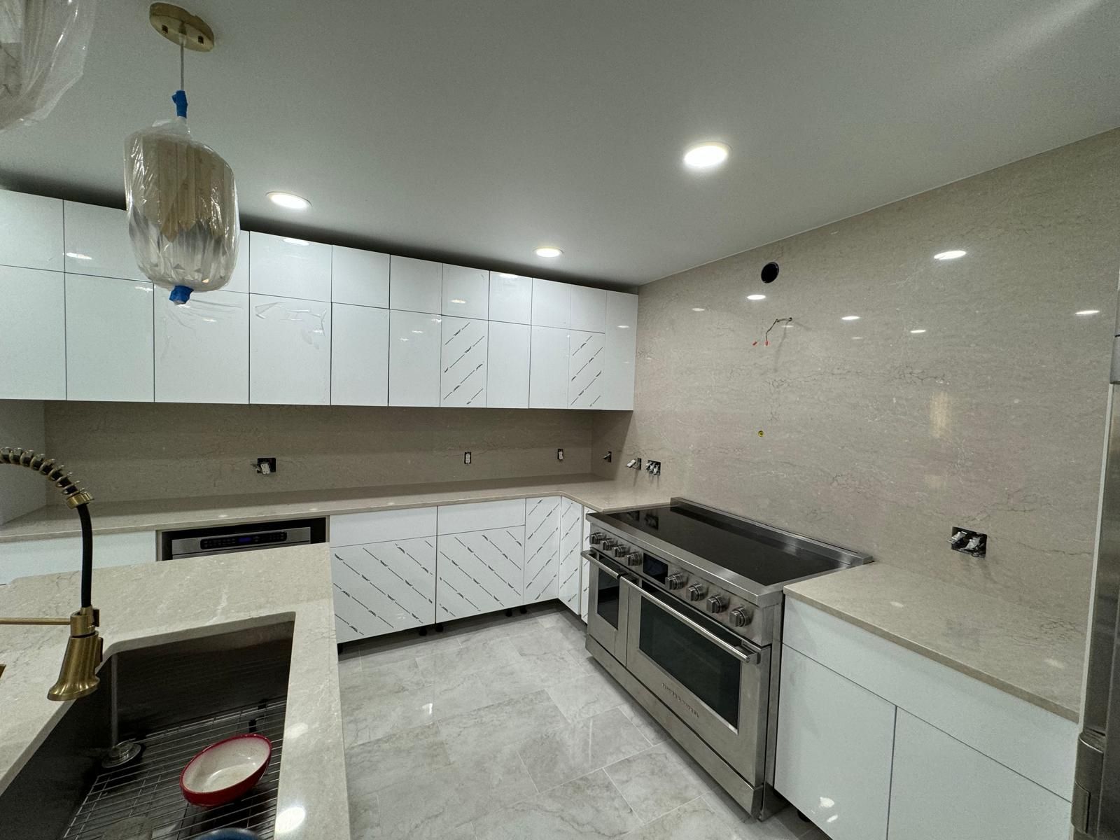 Modern kitchen with white cabinets, stainless steel range, and light countertops.