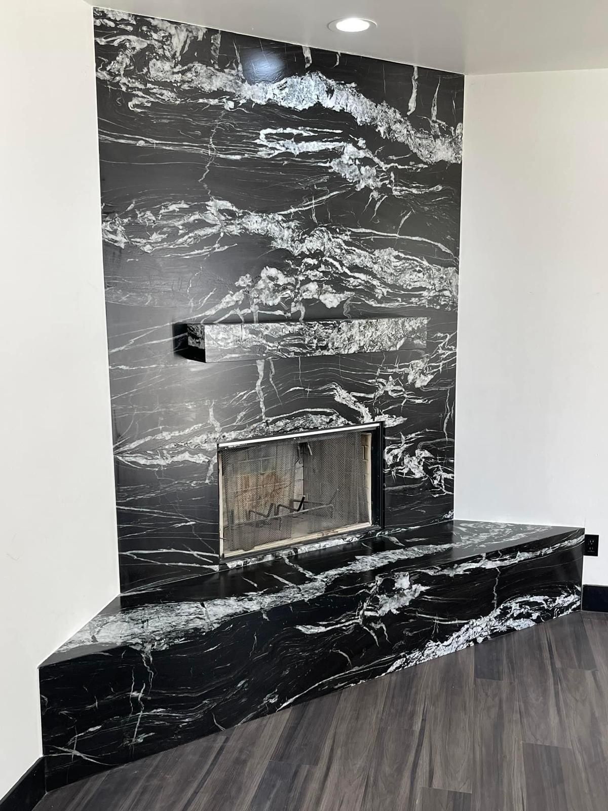 Black and white marble fireplace in a corner setting with a dark floor.
