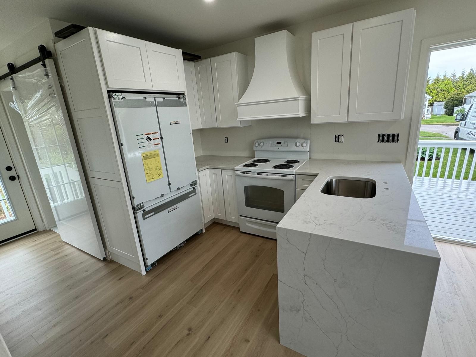 White kitchen with cabinets, appliances, countertops, and a sink.