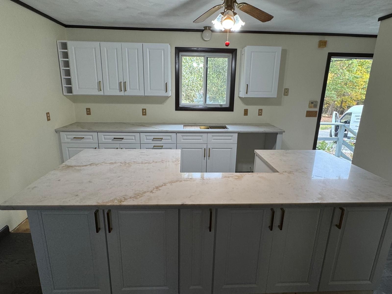 White kitchen cabinets with light countertops and a U-shaped island.