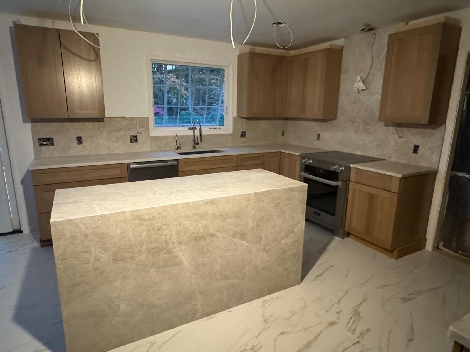 Kitchen remodel with light wood cabinets, gray countertops, and an island.